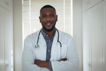 Retrato de un médico afroamericano mirando a la cámara y sonriendo. permanecer en casa en aislamiento durante el bloqueo de cuarentena. - foto de stock