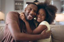 African american man and his daughter embracing on couch. staying at home in self isolation during quarantine lockdown. — Stock Photo