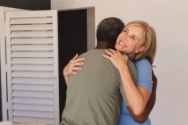 Diverse senior couple standing embracing and smiling. staying at home in isolation during quarantine lockdown. — Stock Photo
