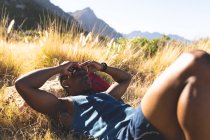Hombre afroamericano haciendo ejercicio al aire libre descansando en una montaña. entrenamiento de fitness y estilo de vida saludable al aire libre. - foto de stock
