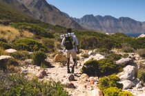 Homem afro-americano exercitando-se ao ar livre caminhadas em uma montanha. treinamento de fitness e estilo de vida saudável ao ar livre. — Fotografia de Stock