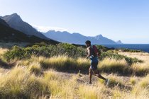Hombre afroamericano haciendo ejercicio al aire libre corriendo en una montaña. entrenamiento de fitness y estilo de vida saludable al aire libre. - foto de stock