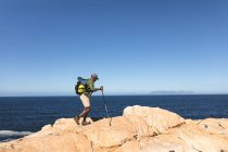 Afrikanisch-amerikanischer Mann beim Outdoor-Wandern mit Stöcken auf einem Berg. Fitnesstraining und gesunder Lebensstil im Freien. — Stockfoto