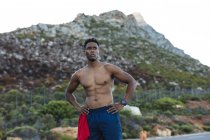 Portrait eines fitten afrikanisch-amerikanischen Mannes, der im Freien auf einer Küstenstraße trainiert. Fitnesstraining und gesunder Lebensstil im Freien. — Stockfoto