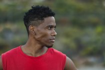 Portrait of fit african american man exercising outdoors looking to a side on a coastal road. fitness training and healthy outdoor lifestyle. — Stock Photo
