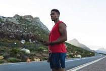 Homem afro-americano a exercitar-se ao ar livre numa estrada costeira. treinamento de fitness e estilo de vida saudável ao ar livre. — Fotografia de Stock