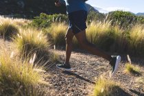 Hombre afroamericano haciendo ejercicio al aire libre corriendo en una montaña. entrenamiento de fitness y estilo de vida saludable al aire libre. - foto de stock