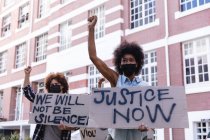 Diverse männliche und weibliche Demonstranten marschieren mit Gesichtsmasken auf, halten Protestschilder hoch und recken die Fäuste. Demonstrationszug für gleiche Rechte und Gerechtigkeit während der 19. Coronavirus-Pandemie. . — Stockfoto