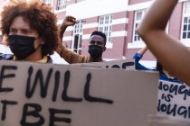 Diverse männliche und weibliche Demonstranten marschieren in Gesichtsmasken mit Protestschildern und recken die Fäuste. Demonstrationszug für gleiche Rechte und Gerechtigkeit während der 19. Coronavirus-Pandemie. . — Stockfoto