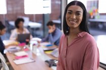 Portrait of mixed race businesswoman in meeting room looking to camera smiling. independent creative design business. — Stock Photo