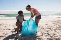 Feliz casal afro-americano usando luvas de látex coletando lixo da praia. eco verão conservação da praia — Fotografia de Stock