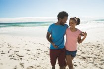 Happy african american couple on beach by the sea embracing. healthy outdoor leisure time by the sea. — Stock Photo