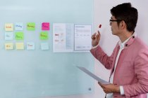 Elegante asiático empresário ler notas segurando documento marcador na parede de vidro. pessoa de negócios no trabalho em escritório moderno. — Fotografia de Stock