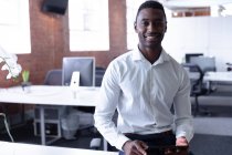 Портрет звичайного афроамериканського бізнесмена, який сидить на столі з планшетом. Бізнесмен на роботі в сучасному офісі.. — стокове фото