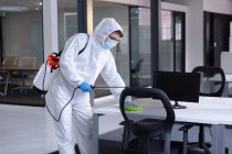 Pulitore indossando salopette igieniche, guanti e maschera viso disinfettante ufficio e mobili. igiene sul posto di lavoro durante coronavirus covid 19 pandemia. — Foto stock