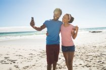 Feliz casal afro-americano na praia junto ao mar tirando selfie. tempo de lazer ao ar livre saudável pelo mar. — Fotografia de Stock