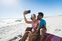 Felice coppia afro-americana sulla spiaggia in riva al mare prendendo selfie. sano tempo libero all'aperto in riva al mare. — Foto stock