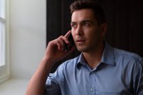 Porträt eines stilvollen kaukasischen Geschäftsmannes, der auf dem Smartphone spricht. Geschäftsmann bei der Arbeit im modernen Büro. — Stockfoto