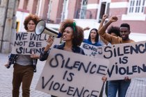 Diverse männliche und weibliche Demonstranten auf dem Marsch halten Protestschilder hoch, recken Fäuste und setzen Megafone ein. Demonstrationszug für Gleichberechtigung und Gerechtigkeit. — Stockfoto