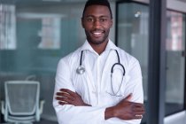 Retrato de um médico afro-americano feliz usando estetoscópio sorrindo de braços cruzados. profissional médico no trabalho. — Fotografia de Stock