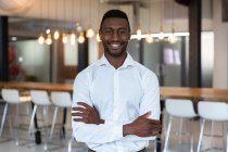 Портрет щасливого афроамериканського бізнесмена з руками схрещували посміхаючись до фотоапарата. Бізнесмен на роботі в сучасному офісі.. — стокове фото