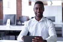 Ritratto di felice uomo d'affari afro-americano casuale usando tablet e sorridendo alla macchina fotografica. uomo d'affari al lavoro in ufficio moderno. — Foto stock