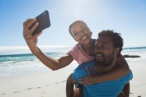 Glückliches afrikanisch-amerikanisches Paar am Strand am Meer, das ein Selfie macht. gesunde Freizeit im Freien am Meer. — Stockfoto