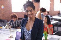 Portrait of mixed race businesswoman at the office looking to camera smiling. independent creative design business. — Stock Photo
