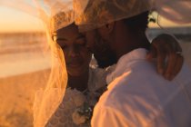 African american couple in love getting married, hugging on beach during sunset. love, romance and wedding beach break summer holiday. romance and beach break summer holiday. — Stock Photo