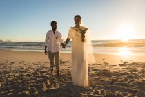 Afroamerikanisches verliebtes Paar, das Händchen haltend am Strand spaziert. Liebe, Romantik und Strandhochzeit Sommerurlaub. — Stockfoto