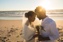Afroamerikanisches verliebtes Paar, das am Strand heiratet und dabei die Stirn berührt. Liebe, Romantik und Strandurlaub. — Stockfoto
