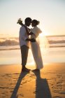 Happy african american couple in love getting married, hugging on beach during sunset. love, romance and wedding beach break summer holiday. — Stock Photo