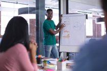 African american businessman at whiteboard giving presentation to diverse group of colleagues. independent creative design business. — Stock Photo