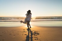 Afroamerikanisches verliebtes Paar, das sich bei Sonnenuntergang am Strand umarmt. Liebe, Romantik und Hochzeit Strandurlaub Sommerurlaub. — Stockfoto