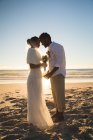 Afroamerikanisches verliebtes Paar, das am Strand heiratet und dabei die Stirn berührt. Liebe, Romantik und Strandurlaub. — Stockfoto