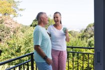 Happy caucasian senior couple having coffee on balcony, talking and smiling. staying at home in isolation during quarantine lockdown. — Stock Photo