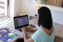 Mulher transgênero de raça mista trabalhando em casa usando laptop. ficar em casa em isolamento durante o confinamento de quarentena. — Fotografia de Stock