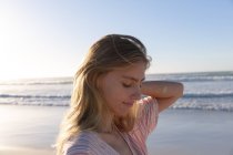 Caucasian woman wearing beach cover up touching her hair at the beach. healthy outdoor leisure time by the sea. - foto de stock