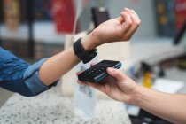 Midsection of woman making contactless watch payment over counter at gym. fitness and leisure time at gym during coronavirus covid 19 pandemic. — Stock Photo
