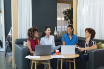 Diverse männliche und weibliche Kollegen aus der Wirtschaft sitzen auf dem Sofa und diskutieren. Lockeres Treffen in Business-Lounge. — Stockfoto