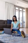 Mixed race transgender woman working at home using laptop talking. staying at home in isolation during quarantine lockdown. — Stock Photo