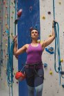 Mujer caucásica sosteniendo cuerdas y preparándose para una escalada en el muro de escalada interior. fitness y tiempo libre en el gimnasio. - foto de stock