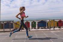 Mulher caucasiana exercitando jogging em um passeio pela praia. tempo de lazer ao ar livre saudável pelo mar. — Fotografia de Stock