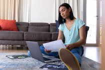 Mixed race transgender woman working at home using laptop. staying at home in isolation during quarantine lockdown. — Stock Photo
