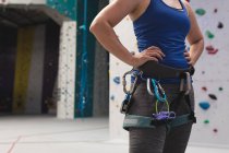 Sección media de la mujer preparándose para escalar en el muro de escalada interior. fitness y tiempo libre en el gimnasio. - foto de stock