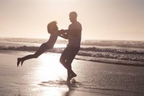 African american father and daughter having fun spinning at the beach. family outdoor leisure time by the sea. - foto de stock