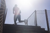 Homem afro-americano a exercitar-se, a subir as escadas num dia ensolarado. treinamento de fitness ao ar livre saudável. — Fotografia de Stock