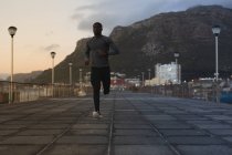 Africano americano exercitando ao ar livre correndo na ponte ao pôr do sol. treinamento de fitness ao ar livre saudável. — Fotografia de Stock