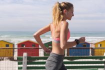 Mulher caucasiana exercitando jogging em um passeio pela praia. tempo de lazer ao ar livre saudável pelo mar. — Fotografia de Stock