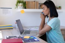 Mulher transgênero de raça mista trabalhando em casa usando laptop tomando café. ficar em casa em isolamento durante o confinamento de quarentena. — Fotografia de Stock